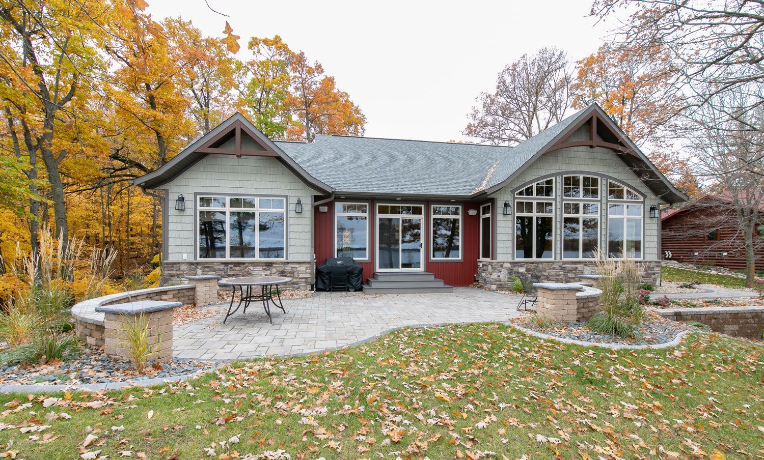 A house with a lot of windows and a patio in front of it.