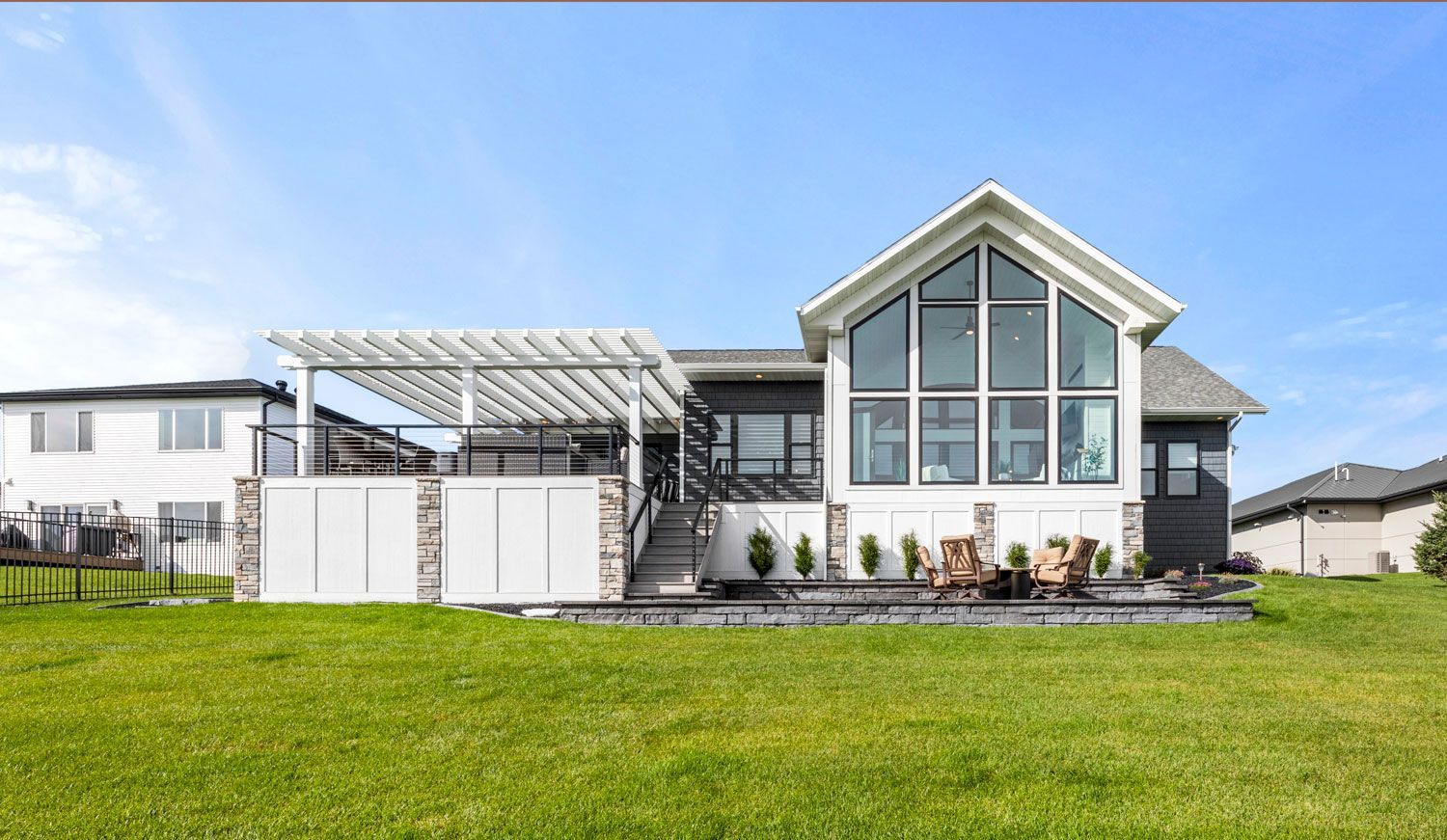 A large house with a lot of windows is sitting on top of a lush green field.