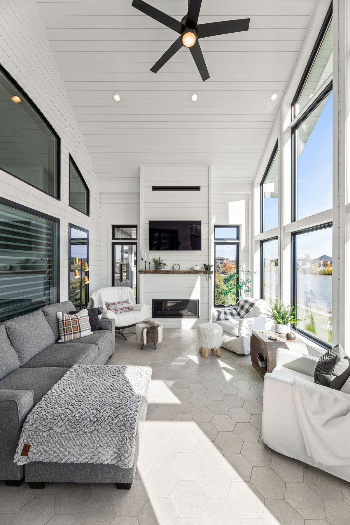 It is a living room with a lot of windows and a ceiling fan.