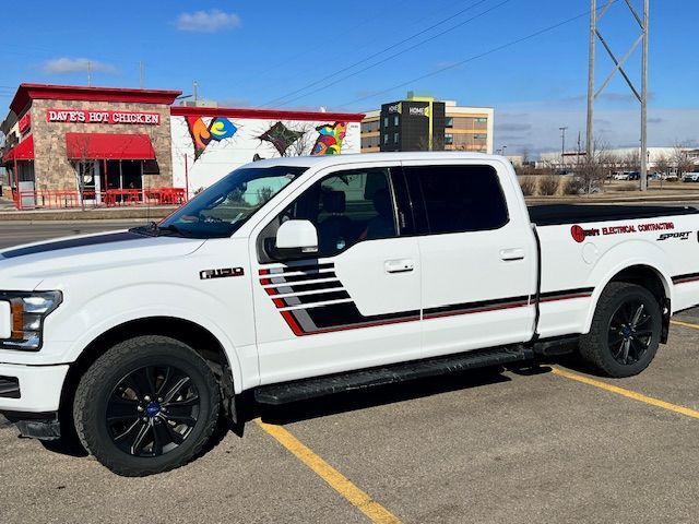 A white truck is parked in a parking lot in front of a restaurant.