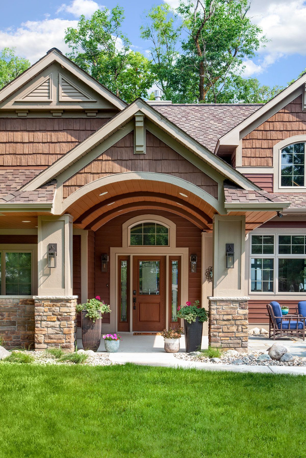 A large house with a porch and a large lawn in front of it.
