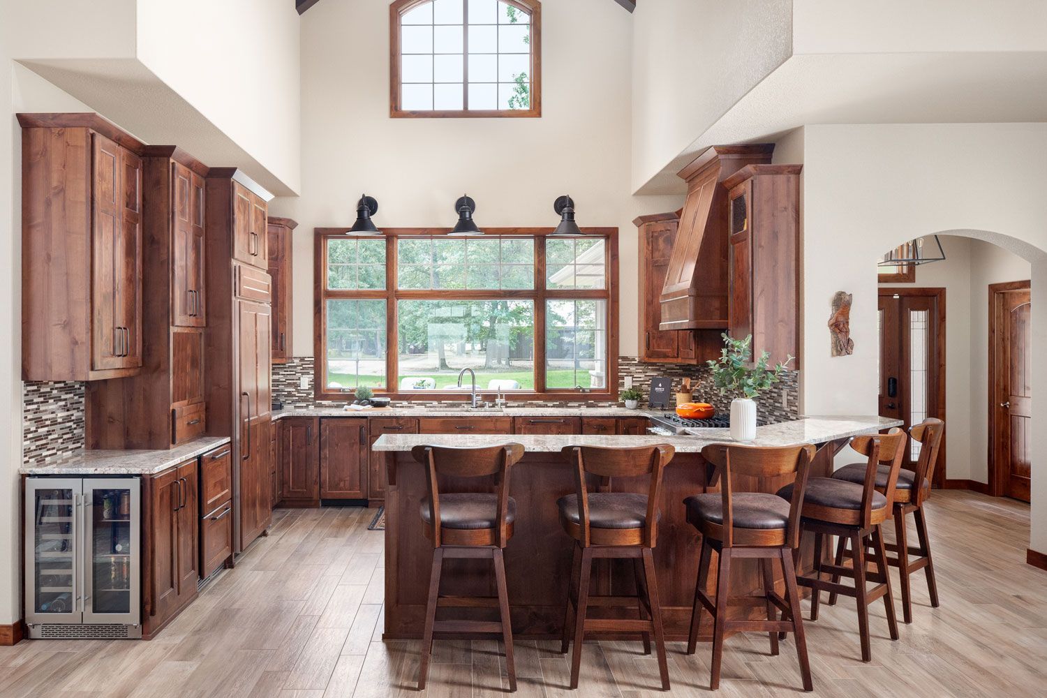 A kitchen with wooden cabinets and stools and a large island.