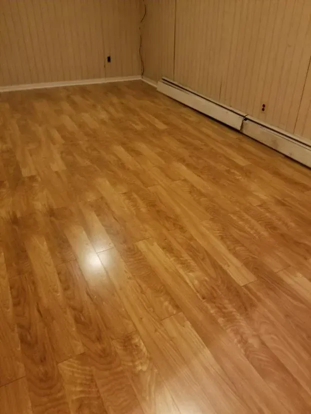 Wood-look flooring in a room with beige paneled walls. A heating unit is along one wall.