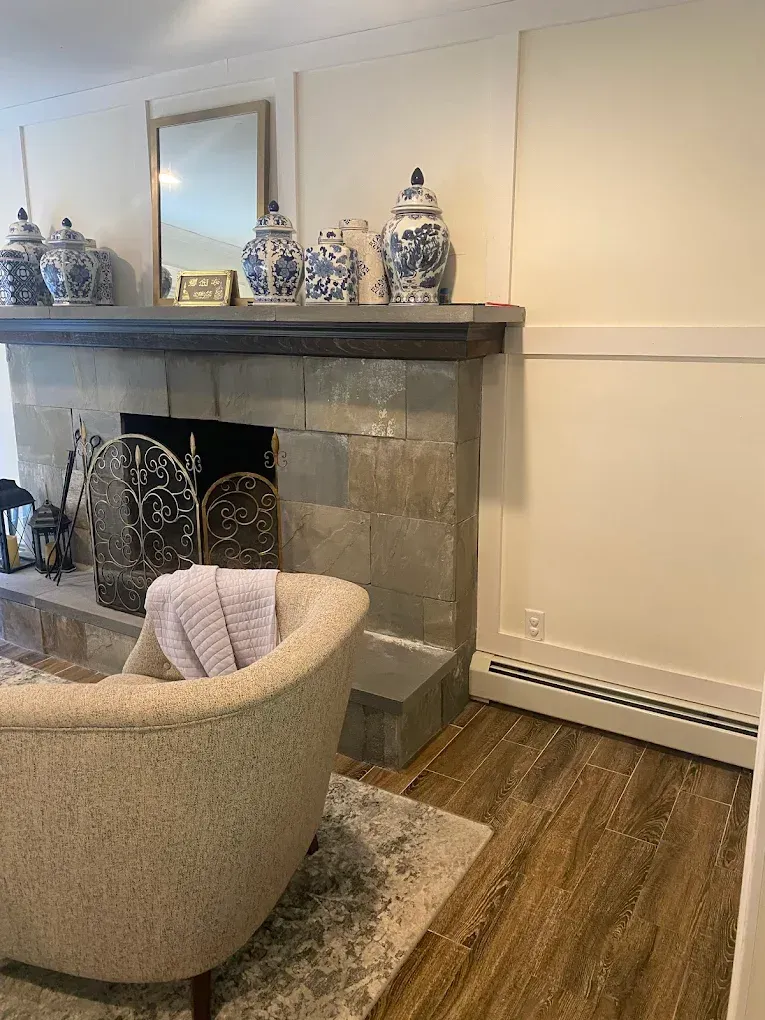 Fireplace with blue and white vases, a chair, and wood flooring.