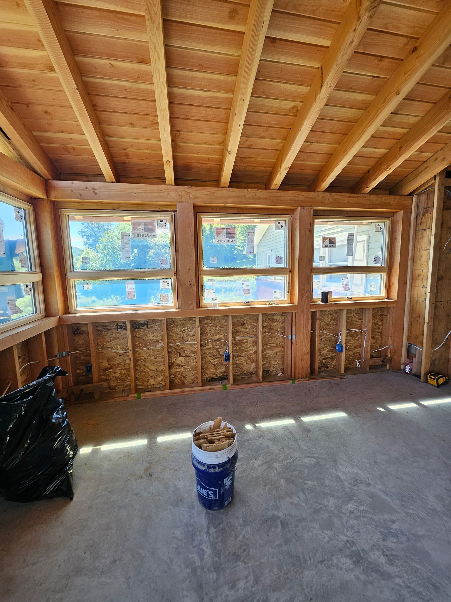 Construction site interior with windows, wooden frame, insulation, and a bucket.