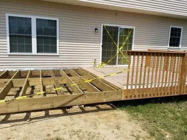 Partially constructed deck with yellow caution tape around the sliding glass door.