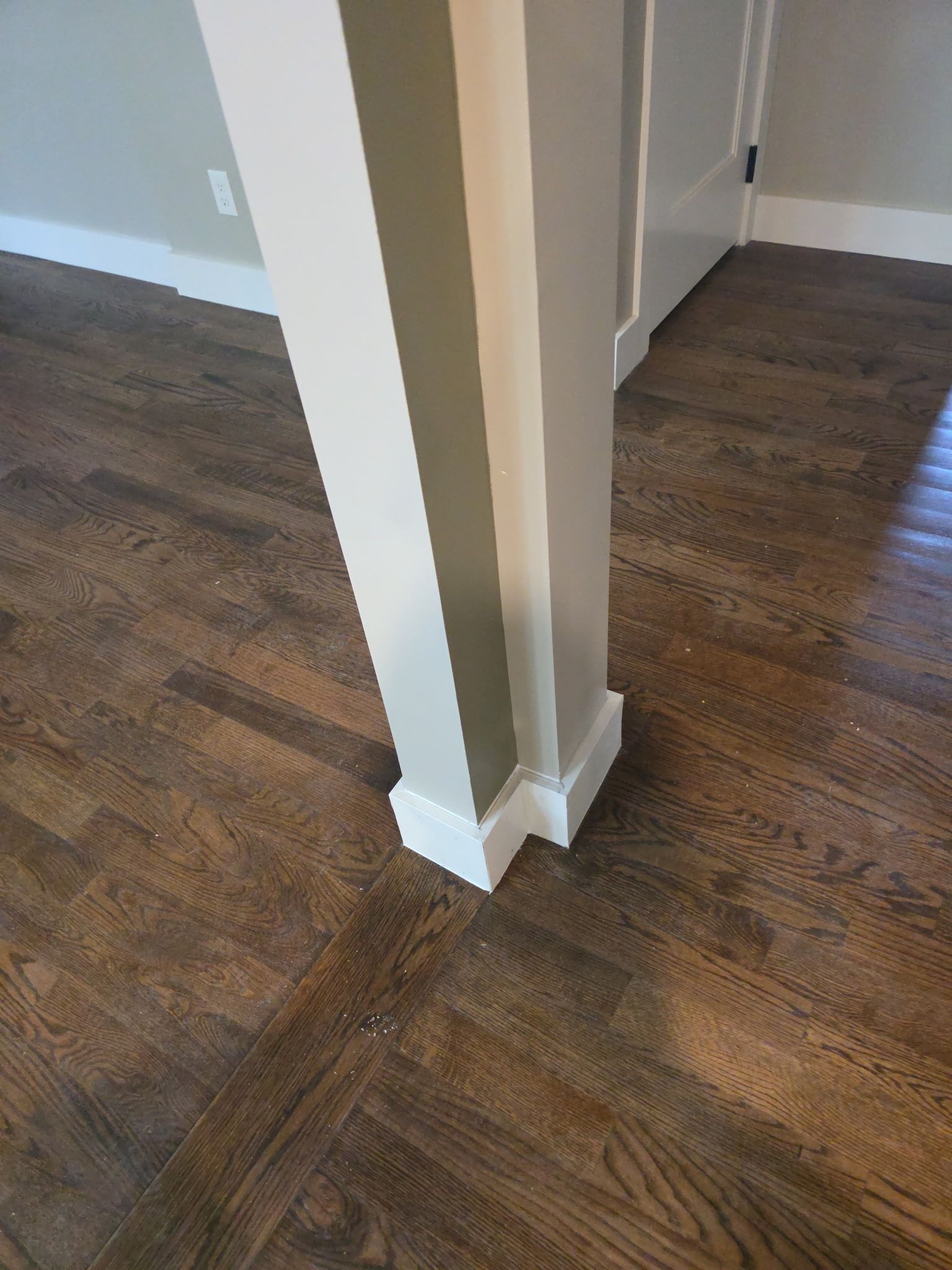 White painted structural column on hardwood floor.