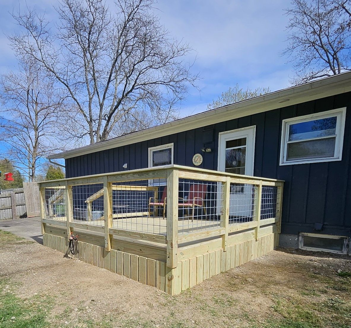 Wooden deck with clear panels attached to a dark blue house.