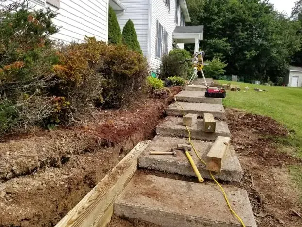 Construction in progress: Steps being rebuilt with wooden forms. Earth and tools visible.