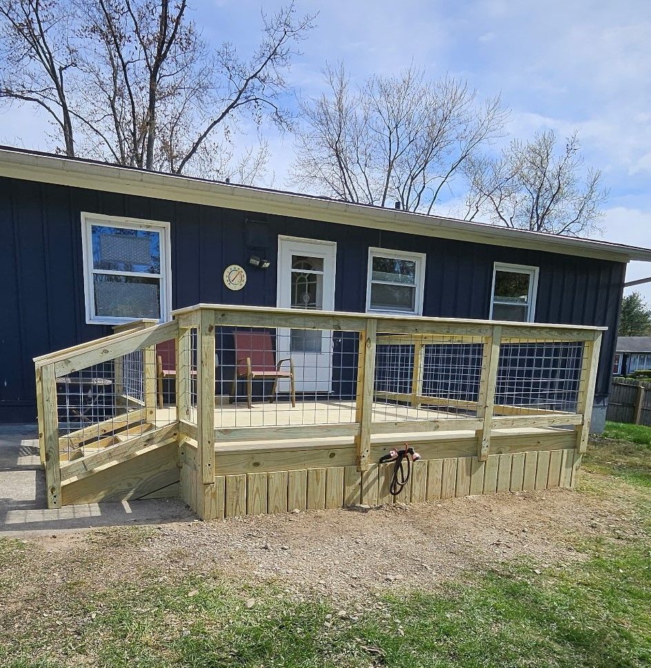 Wooden deck with metal railing in front of a dark blue house.