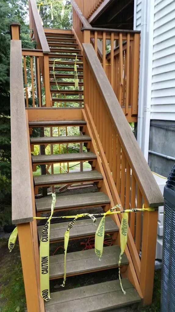 Wooden outdoor stairs with yellow caution tape; likely damaged.