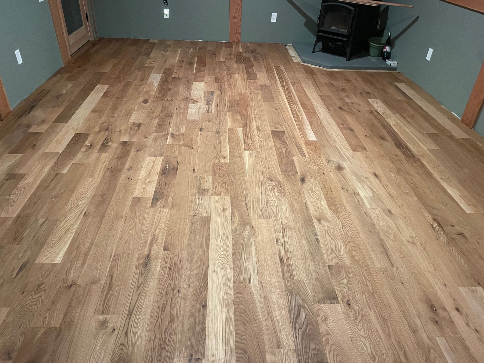 Wooden floor inside a room with a stove in the corner. Light brown planks.