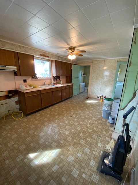 Kitchen with brown cabinets, beige floor, and a vacuum cleaner.