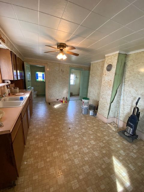 Kitchen with brown cabinets, pink countertops, and a patterned floor. Open doorways lead to other rooms.