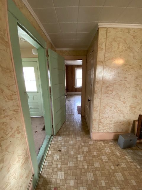 Hallway with patterned flooring and beige wall paneling. Light green doors and doorway on the left.