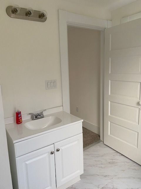White bathroom with vanity, door, and light fixture.