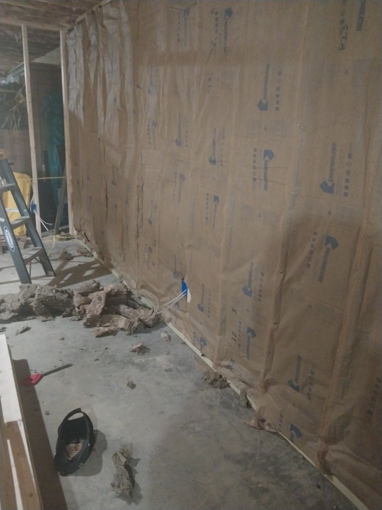 A room under construction with brown insulation, concrete floor, and wood framing.