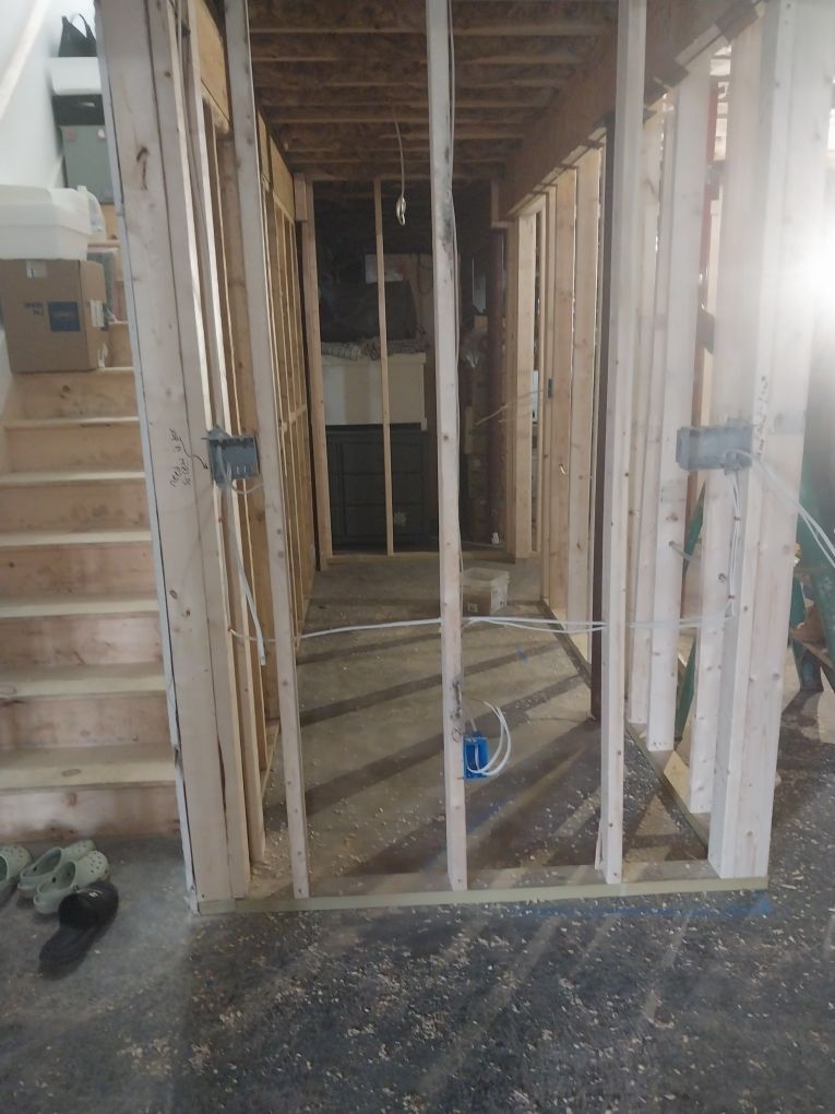 Basement framing under construction; stairs on left, hallway, electrical boxes.