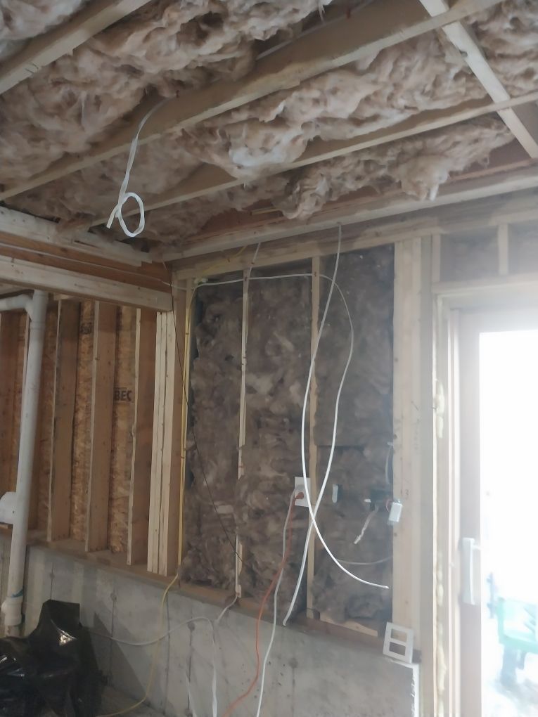 Framed wall with electrical wiring and insulation visible; construction in progress.