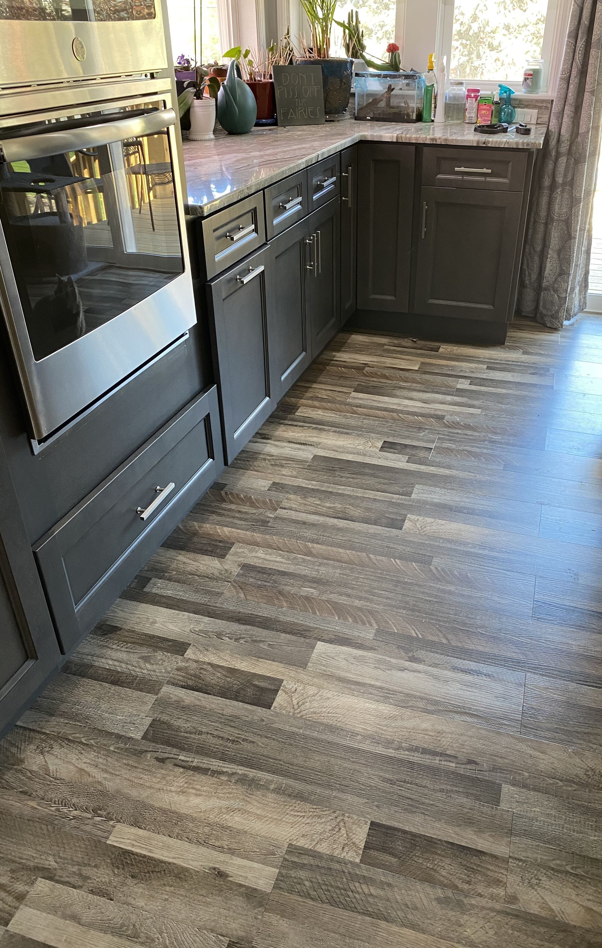 Kitchen with gray cabinets, wood-look floors, and a stainless steel oven.