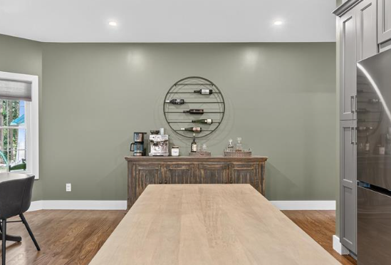 Kitchen with a wooden island, antique-style cabinet, wine rack, and green wall; hardwood floors.