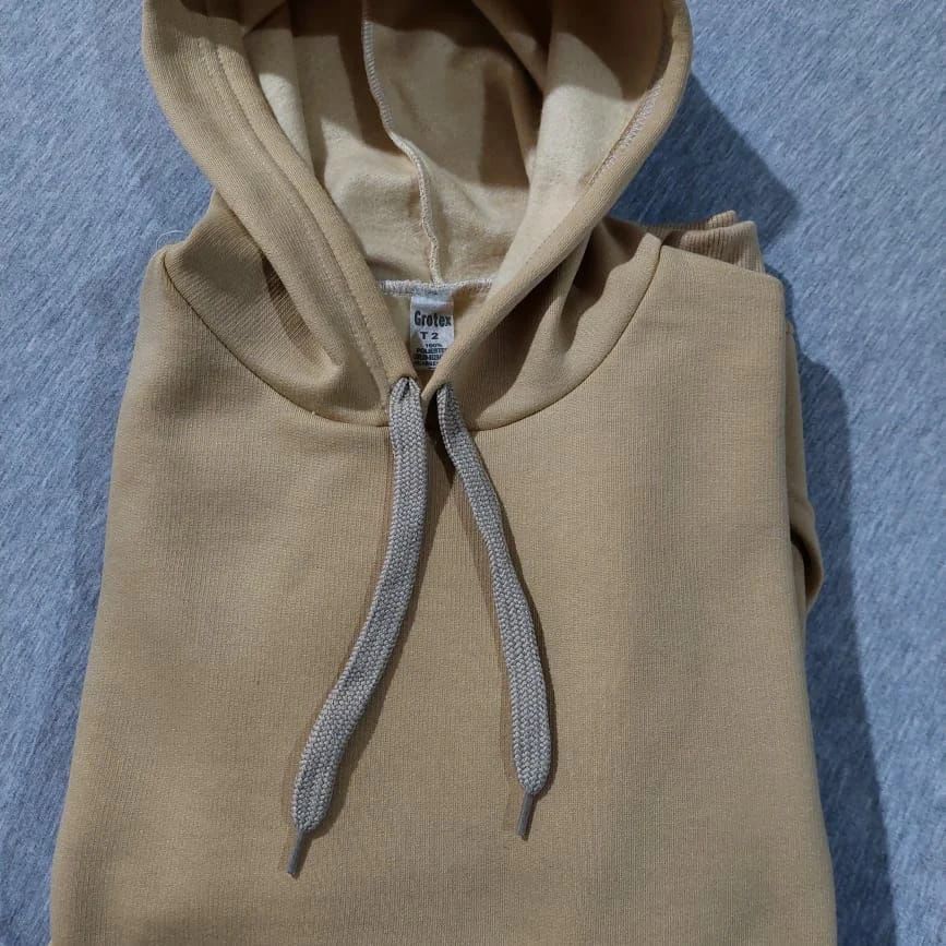 Una sudadera con capucha color canela y cordones grises está sobre una tela azul.