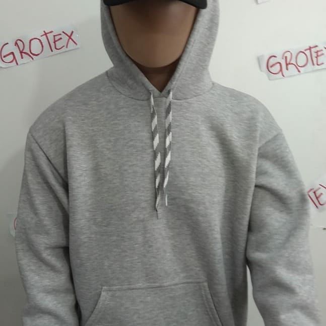 Una sudadera con capucha color canela y cordones grises está sobre una tela azul.