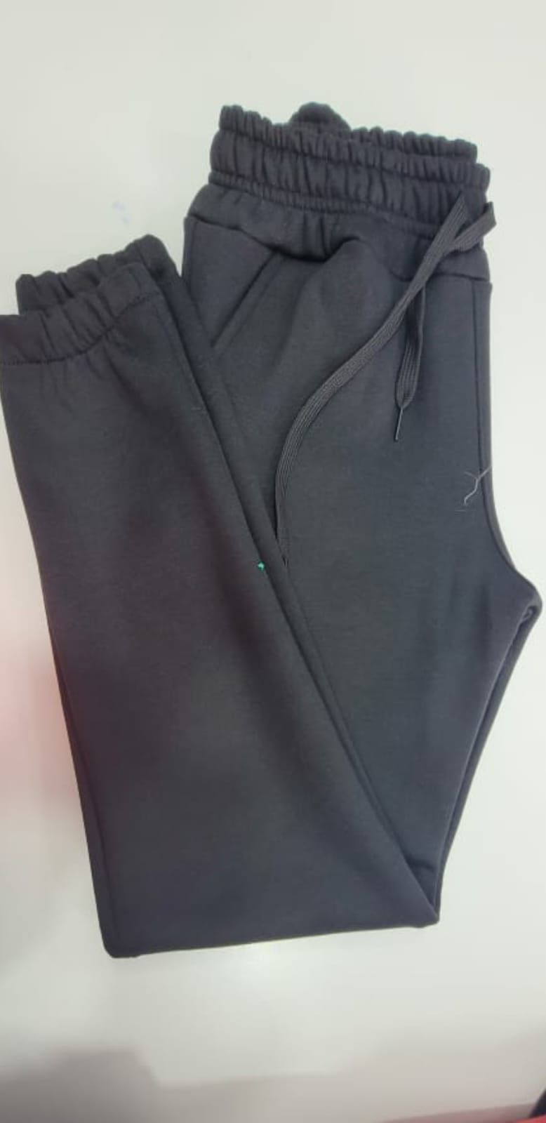 Un par de pantalones deportivos grises están sobre una mesa blanca.