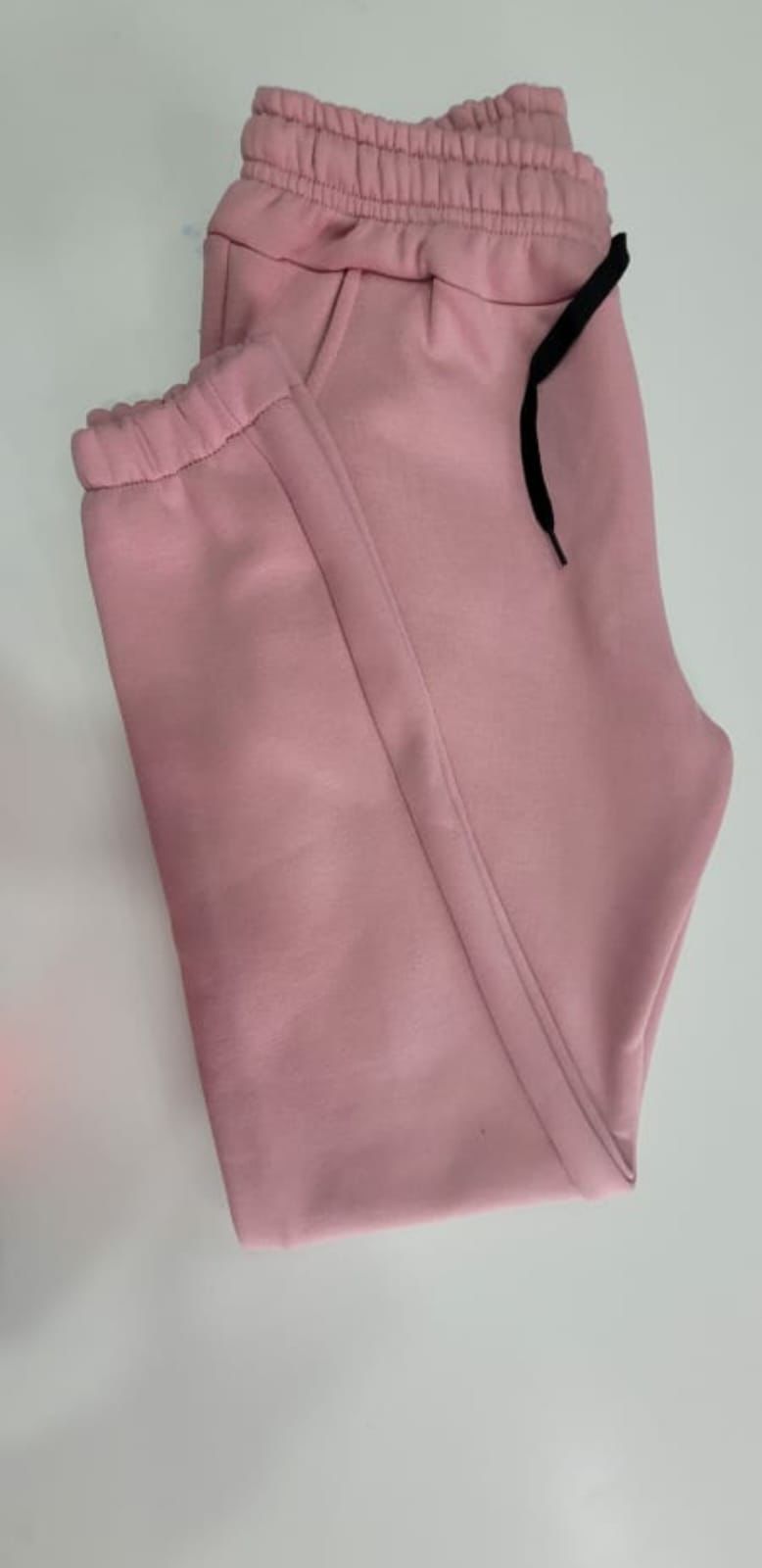 Un par de pantalones deportivos grises están sobre una mesa blanca.