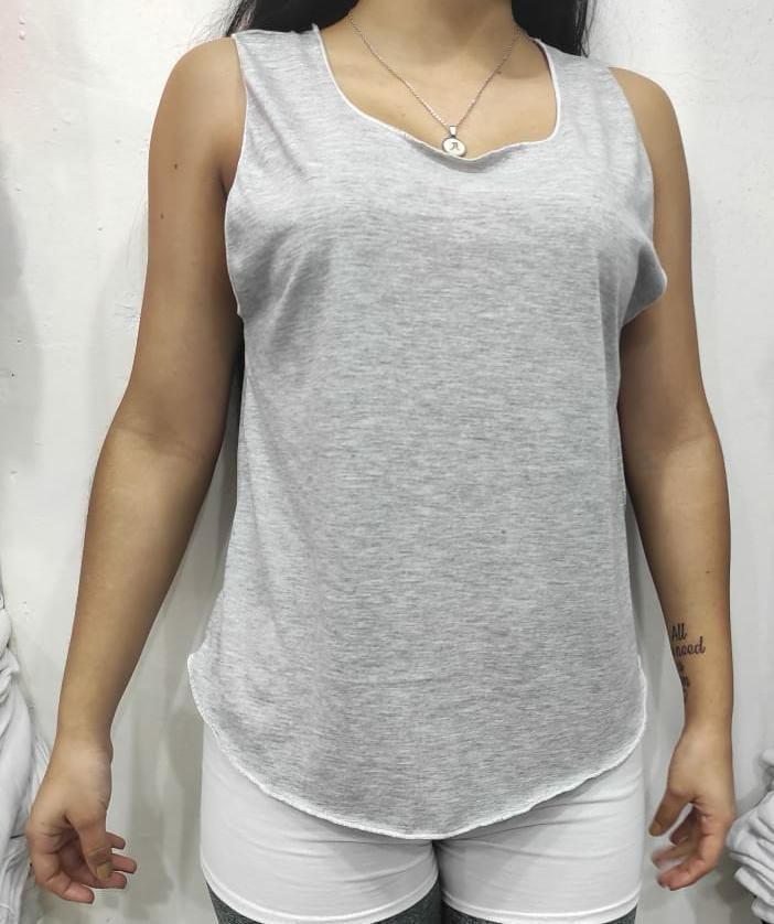 Una mujer lleva una camiseta gris y pantalones cortos blancos.