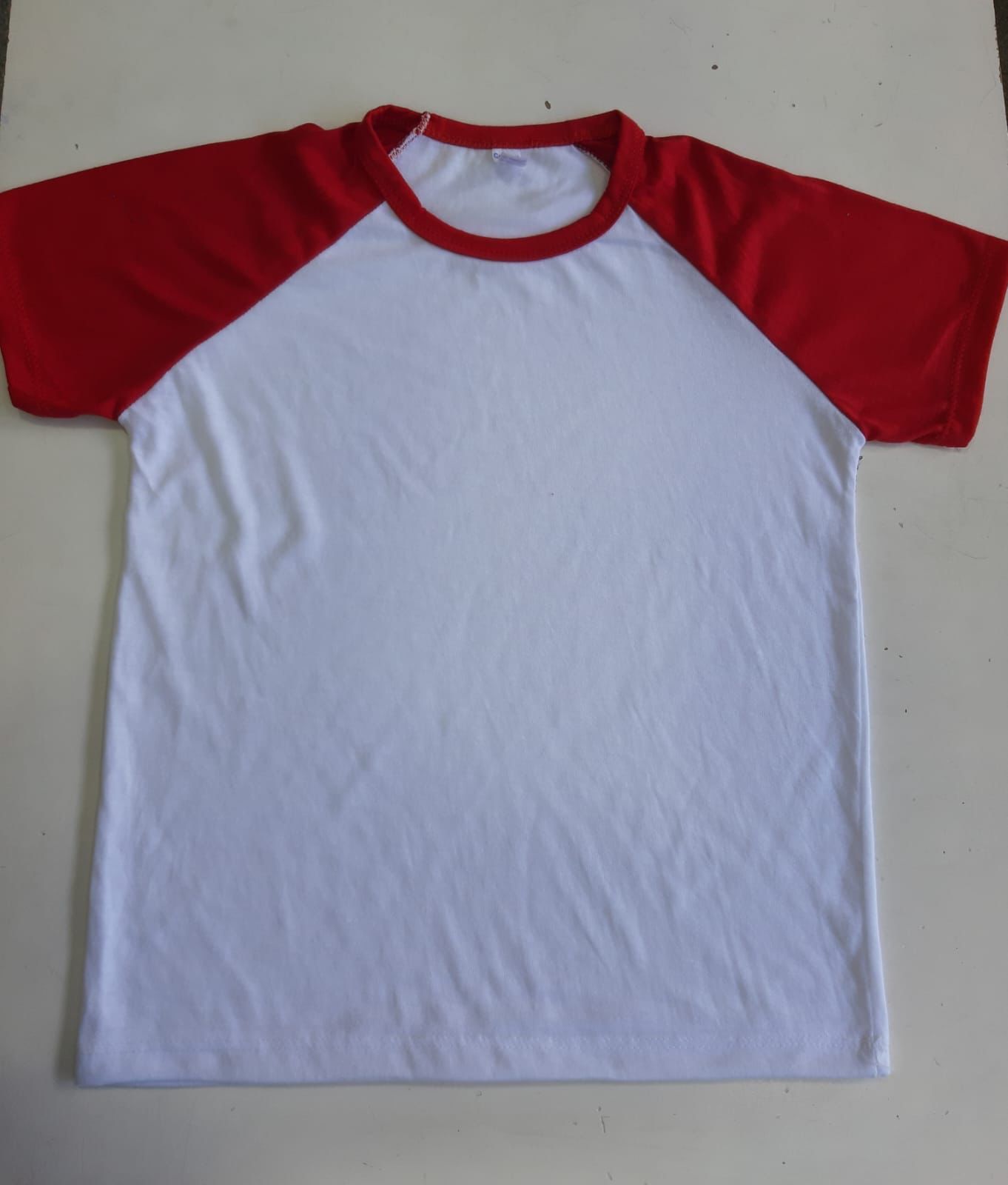 Una camiseta blanca con mangas rojas está sobre una mesa