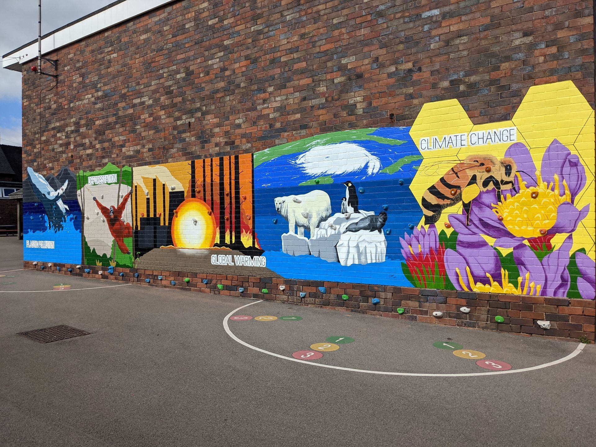 Colorful mural on brick wall depicting nature scenes: birds, sunset, polar bears, and a bee on a flower.
