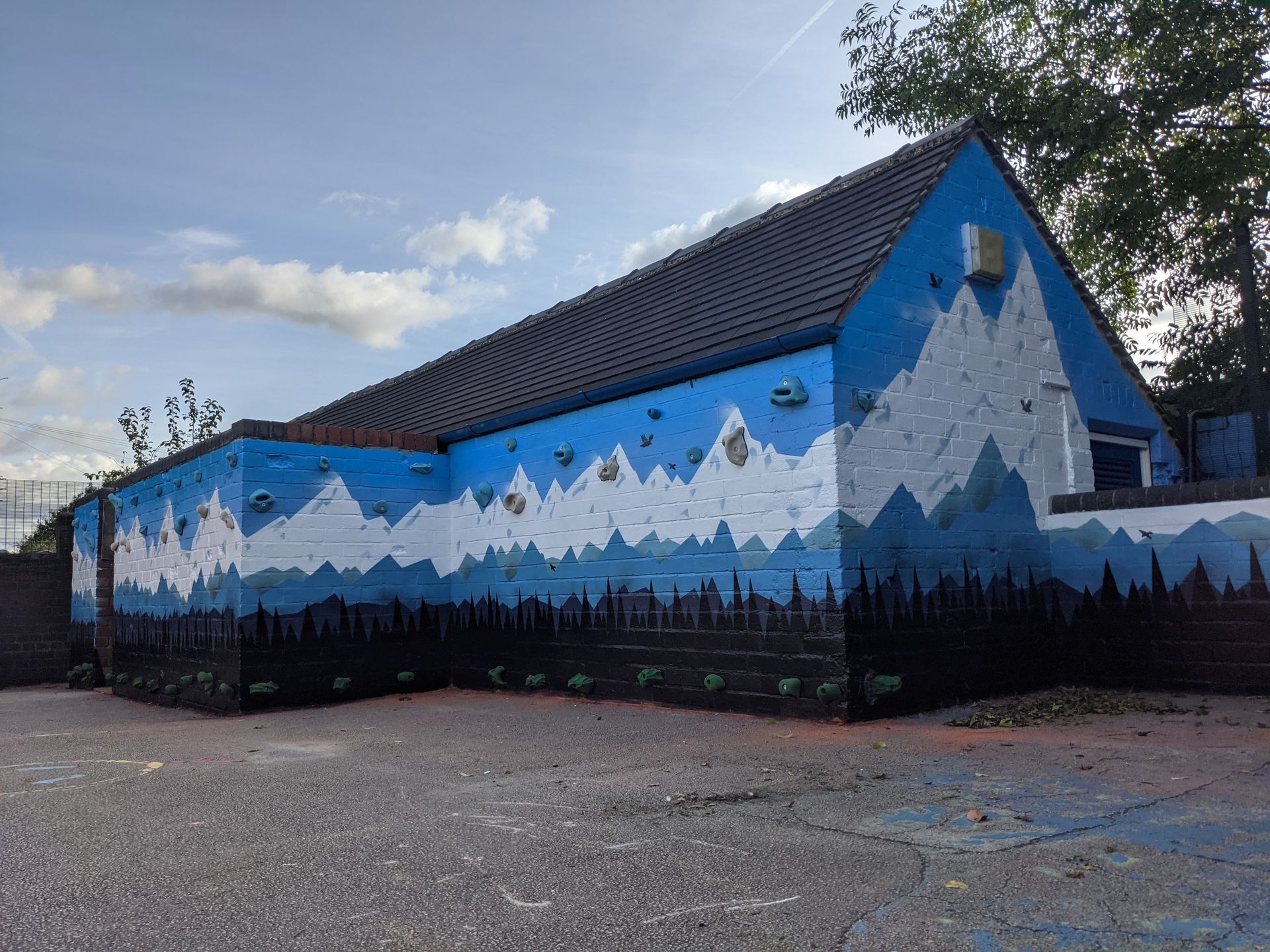 Building with a blue and white mountain mural, against a blue sky.