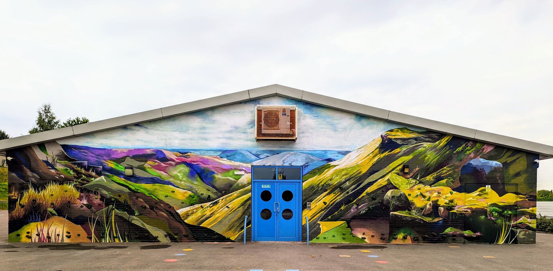 Building with a colorful mural of a landscape; blue door.