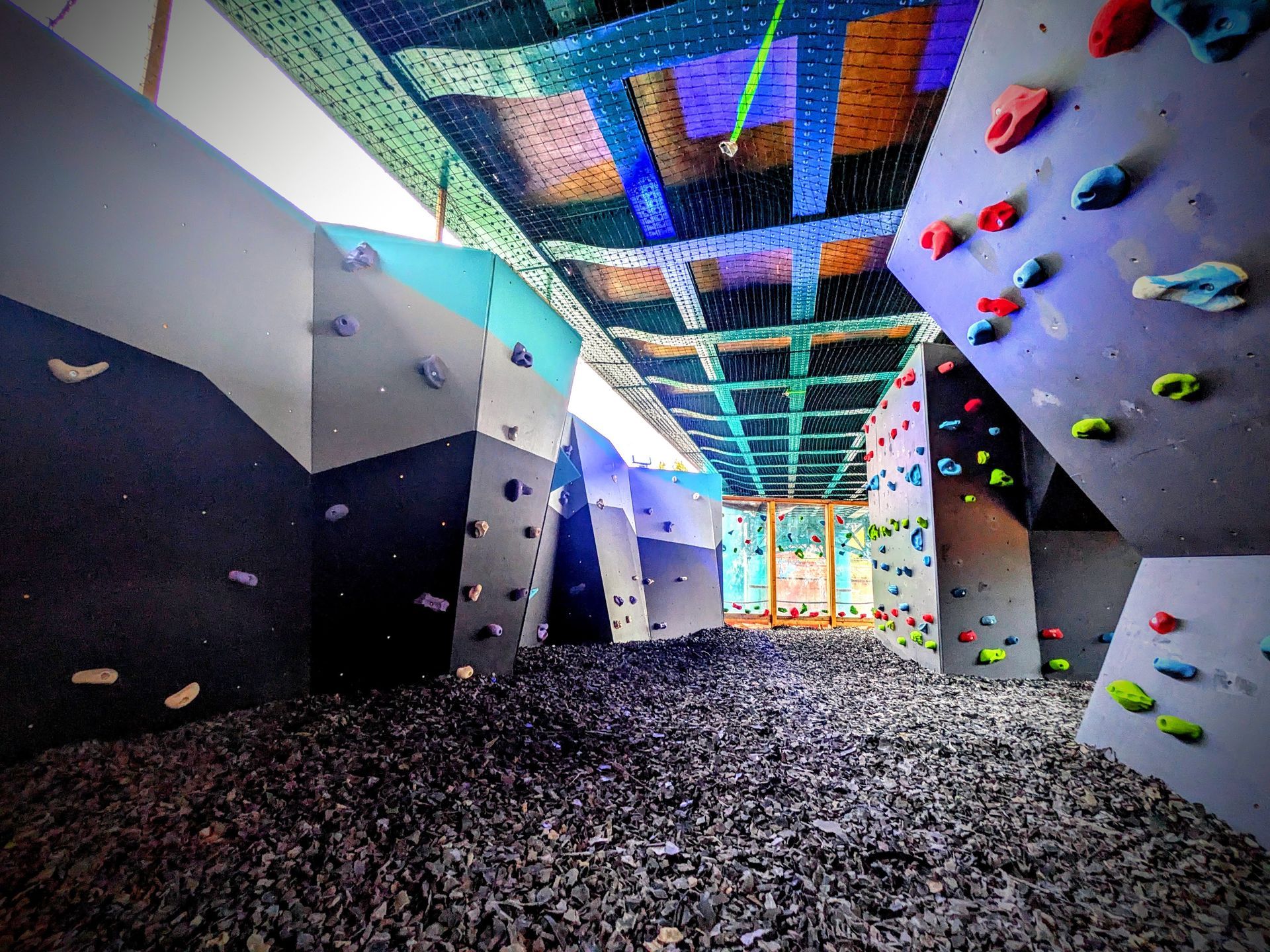Indoor climbing gym with colorful holds on angled walls, safety mats below.