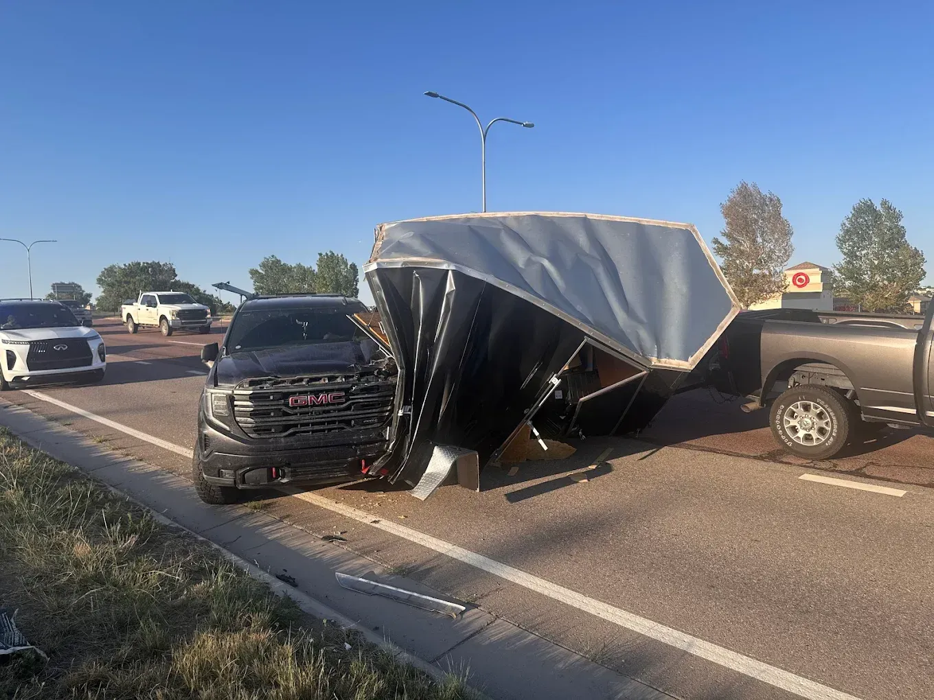 Woman in straw hat smiles, holding wine glass near a lake.