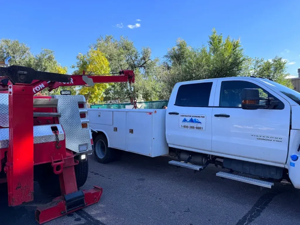 Woman in straw hat smiles, holding wine glass near a lake.