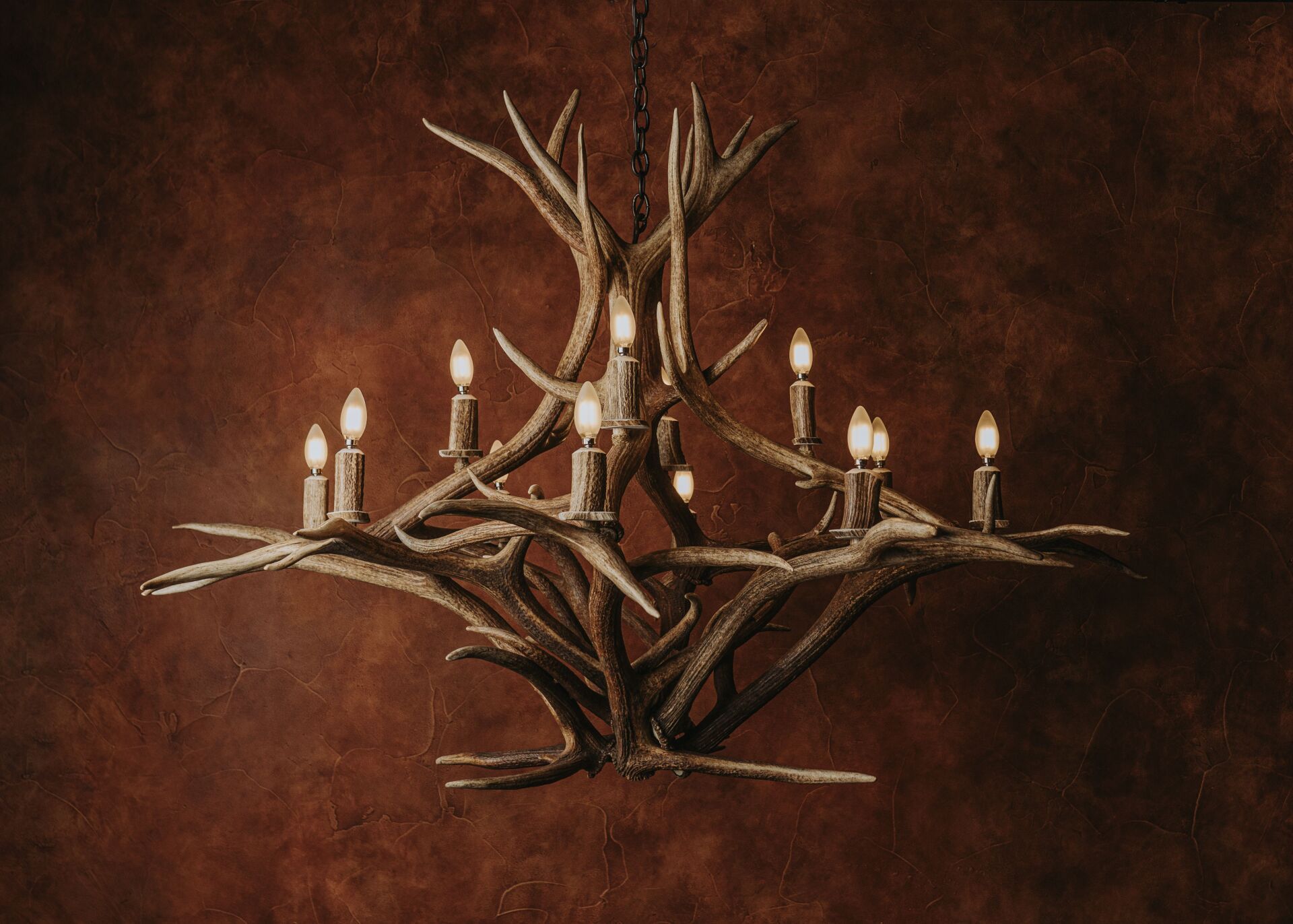 A chandelier made of antlers and candles is hanging from the ceiling.
