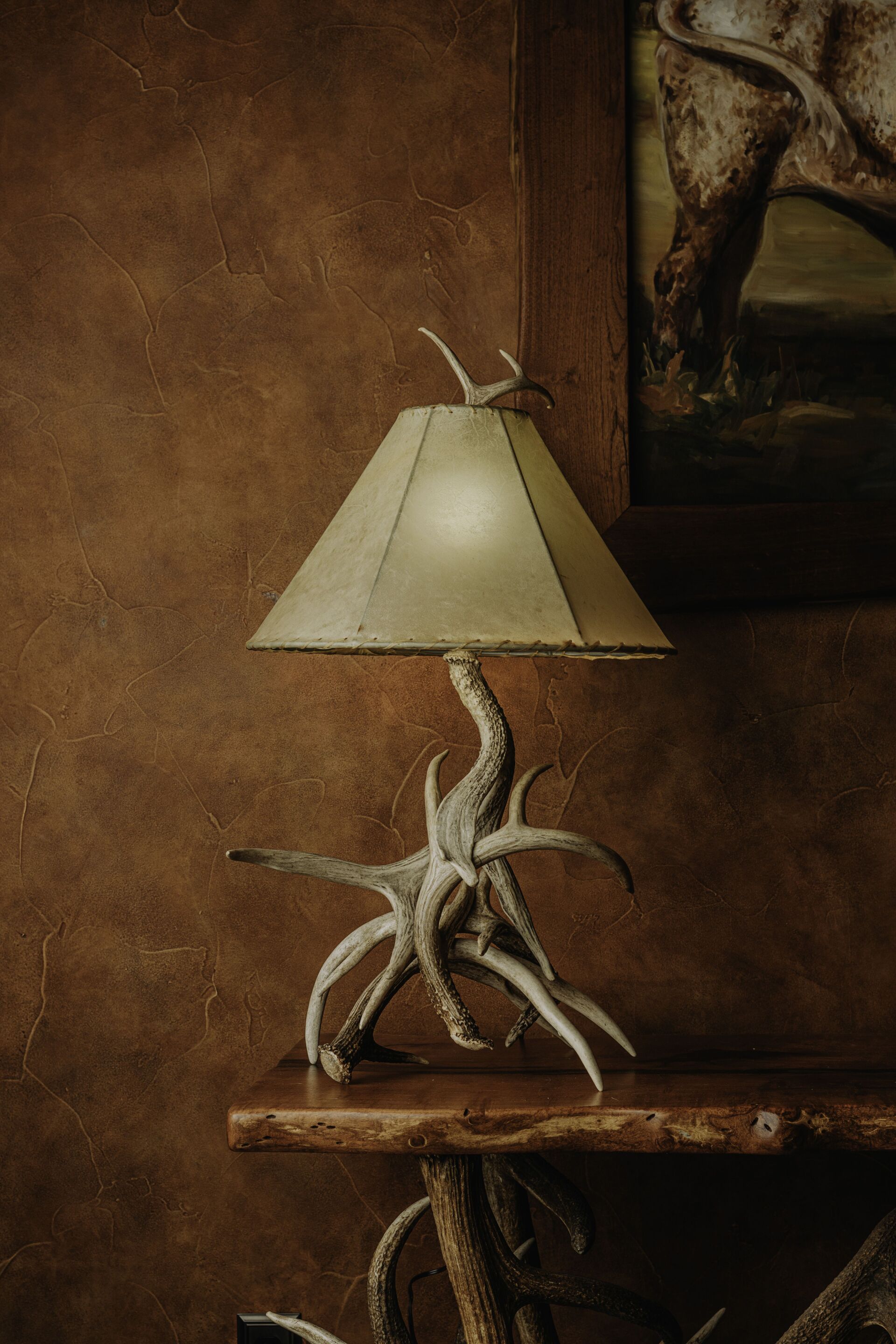A lamp made of antlers is sitting on a wooden table.