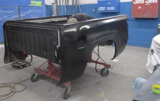 A black truck bed is sitting on a red cart in a garage. Auto Body Repair in Colville, WA