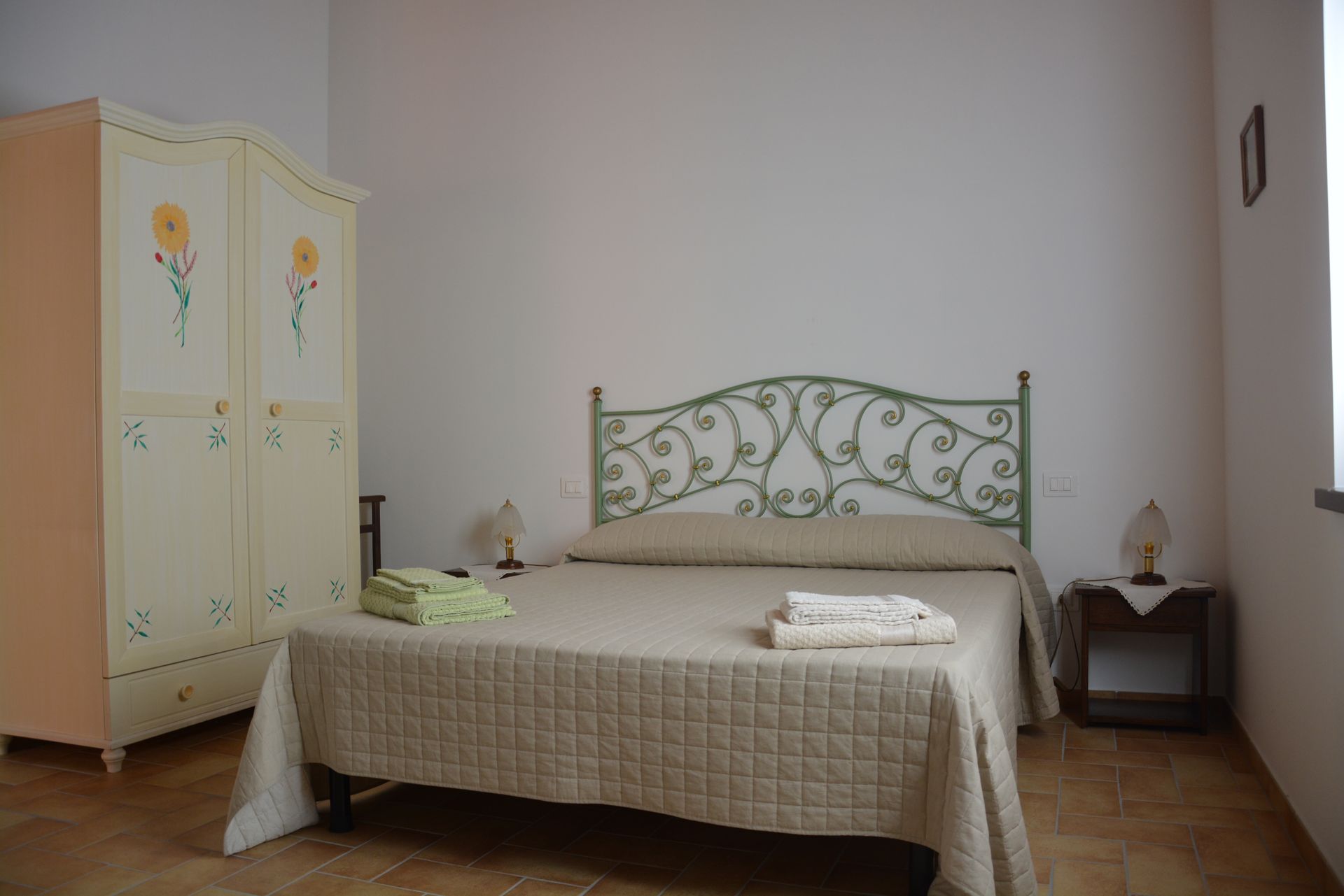 Camera da letto con letto, armadio floreale, comodino e finestra.