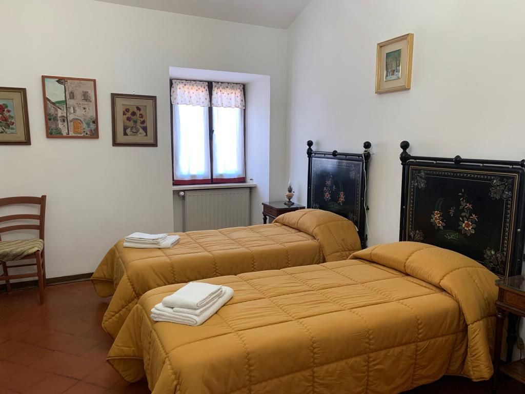 Due letti singoli in una stanza con piumoni gialli, testiere scure e opere d'arte alle pareti.