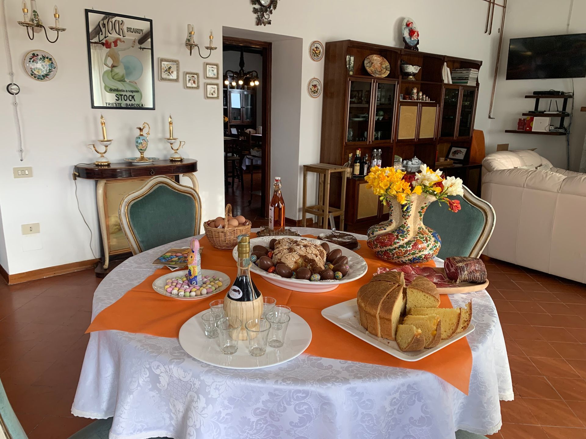 Un tavolo rotondo apparecchiato per un pasto con cibo, bevande e fiori in una stanza arredata.