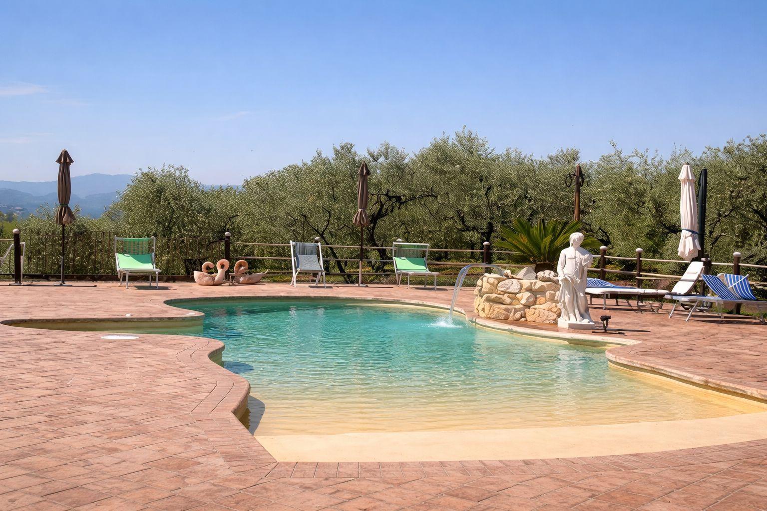 Primo piano di una piscina verde chiaro con due getti circolari, circondata da un bordo di colore chiaro e da una bordatura in mattoni.