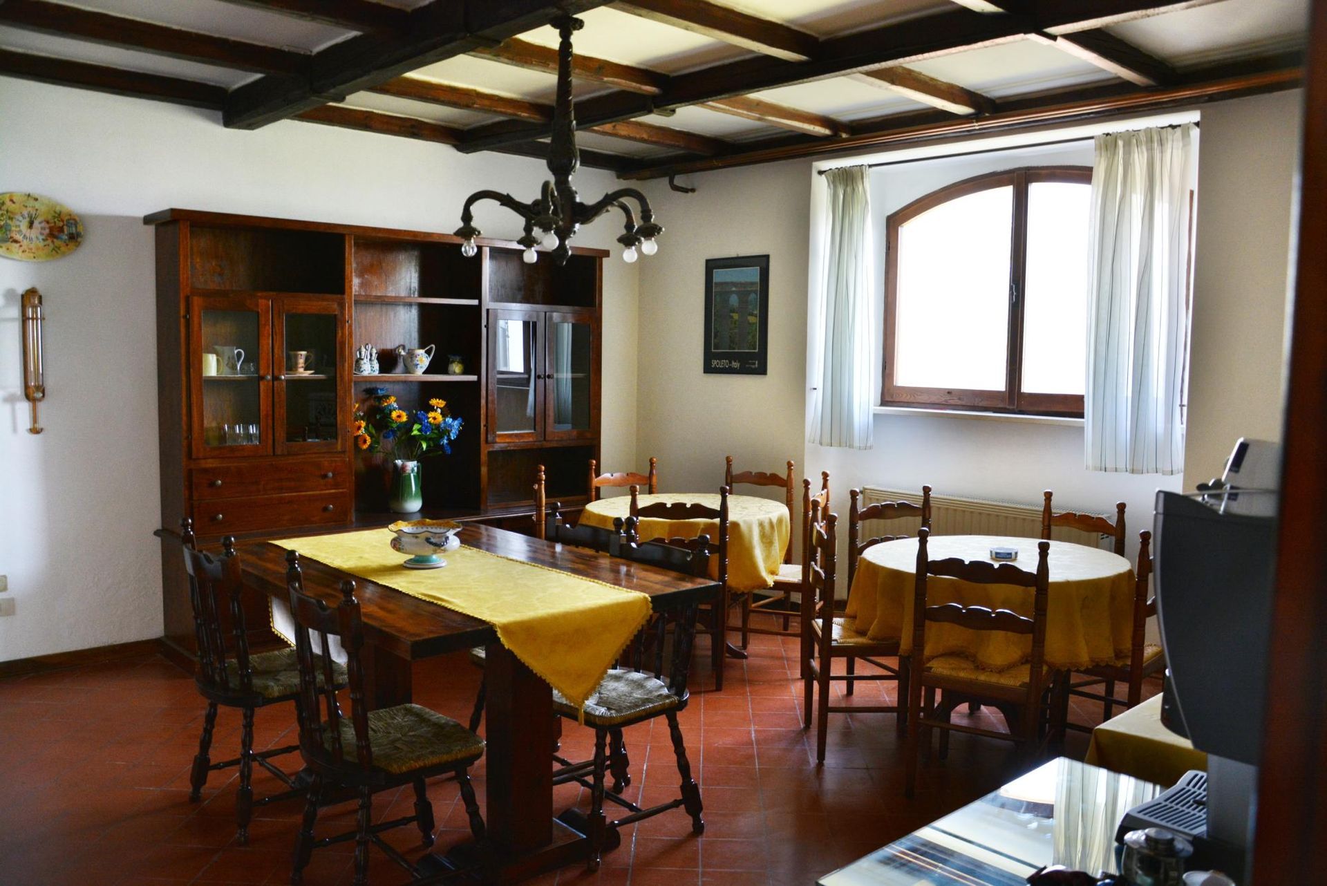 Edificio in stucco rosa con porta marrone, ringhiera in bambù e vista parziale su una collina.