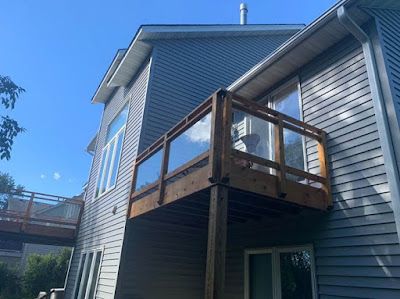 A house with a wooden deck and a glass railing.