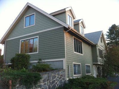 A large green house with a stone wall in front of it