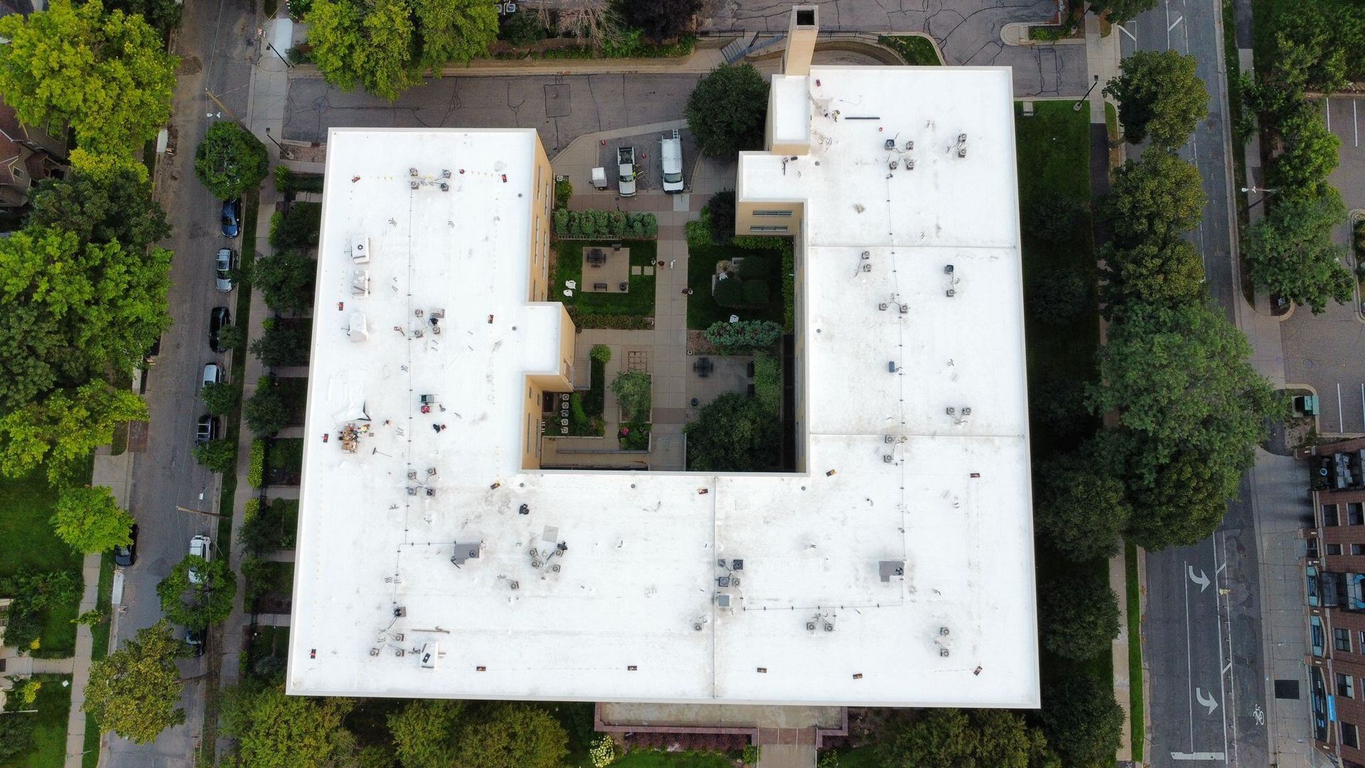 An aerial view of a large building with a white roof surrounded by trees.