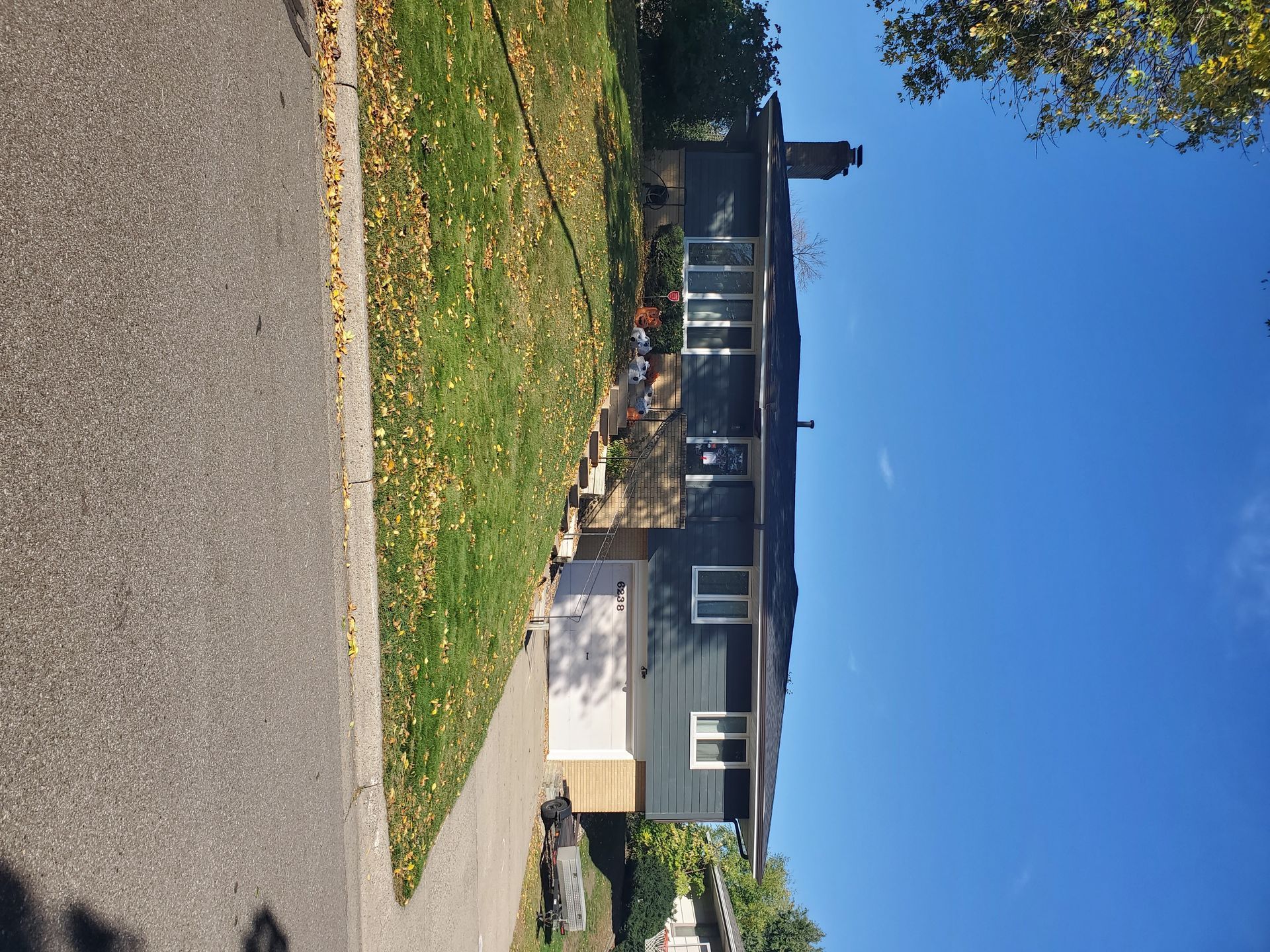 A house is sitting on the side of the road next to a sidewalk.