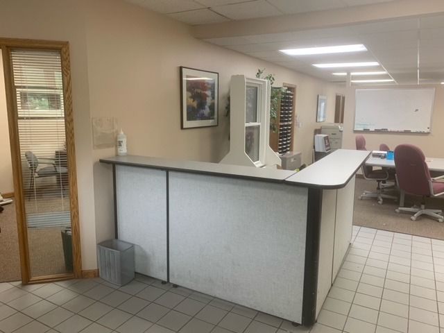 A reception desk in an office with a trash can in front of it